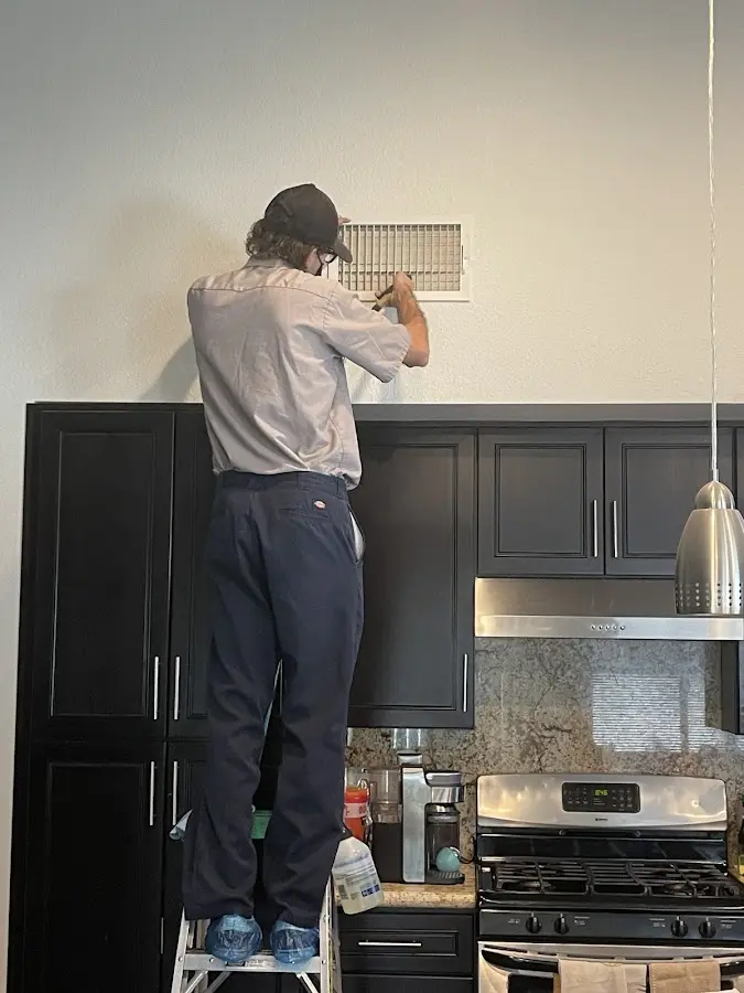 Technician inspecting an air vent during HVAC service in Silver City